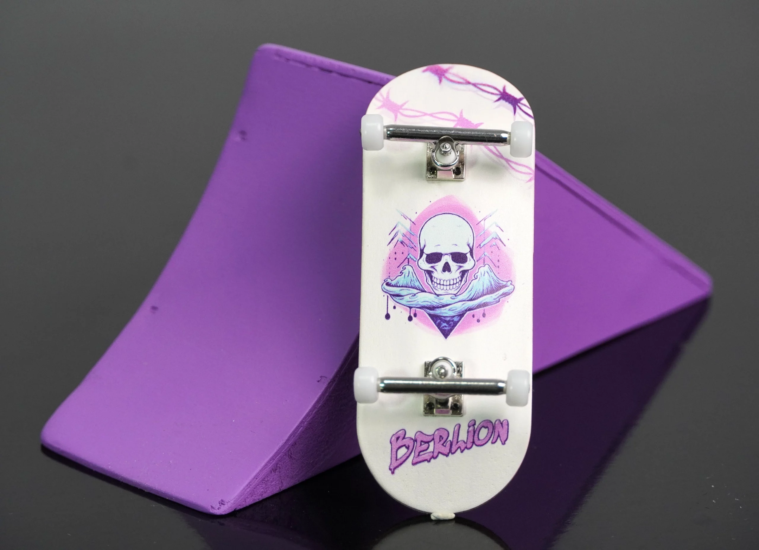Fingerboard Berlion realizando trucos sobre rampa morada.