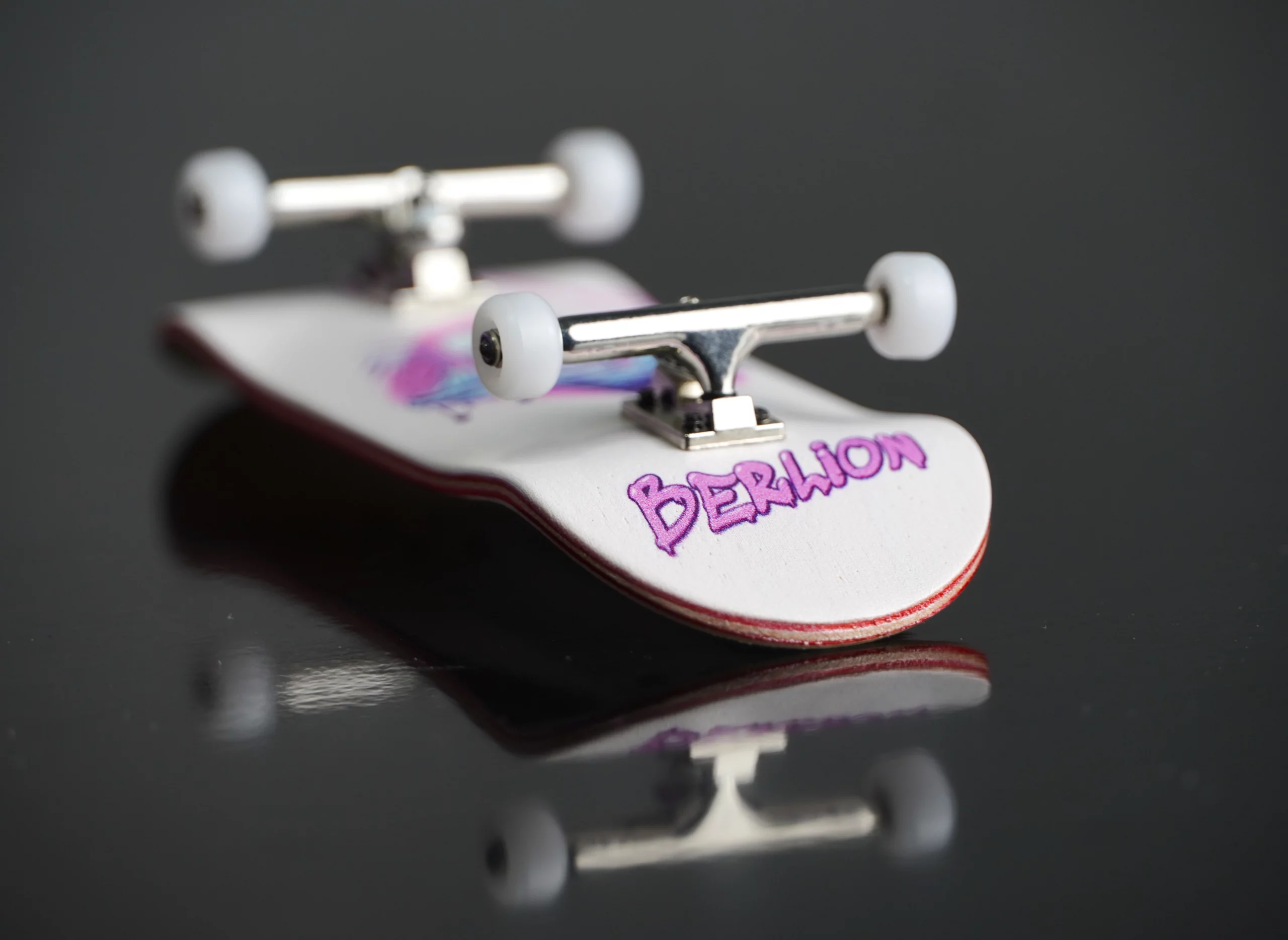 Vista lateral del fingerboard Berlion con logo violeta y ruedas blancas.